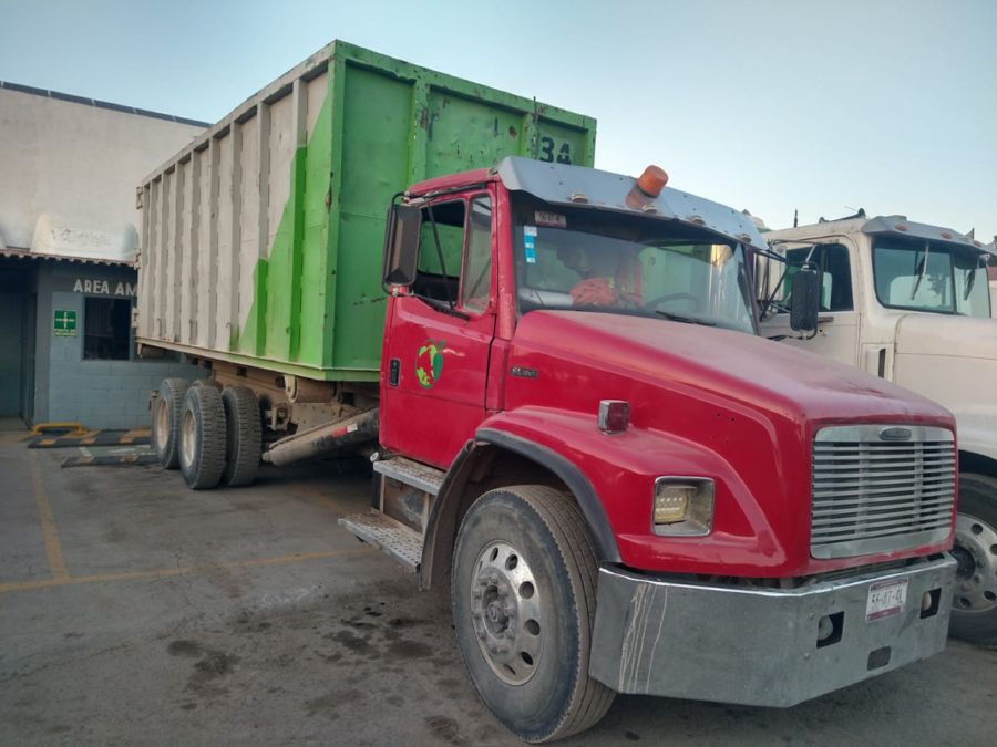 Camión rojo de CRA con contenedor en la planta